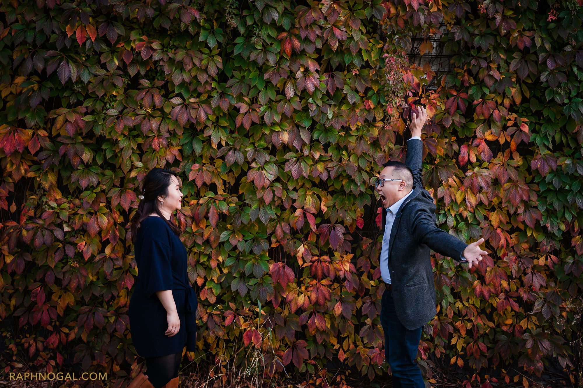 couple about to hug by leaf wall