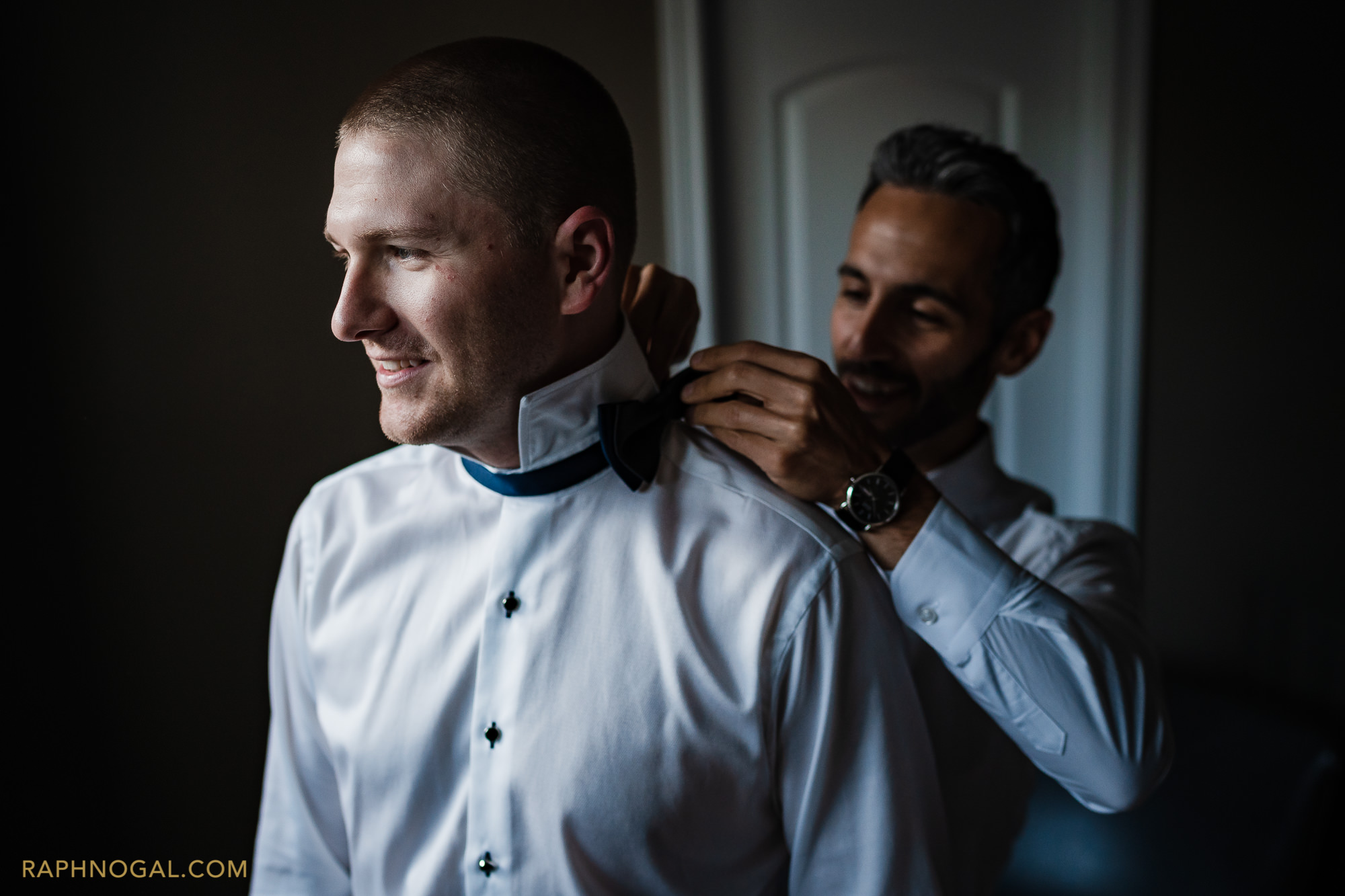 groom getting bow tie put on by best man