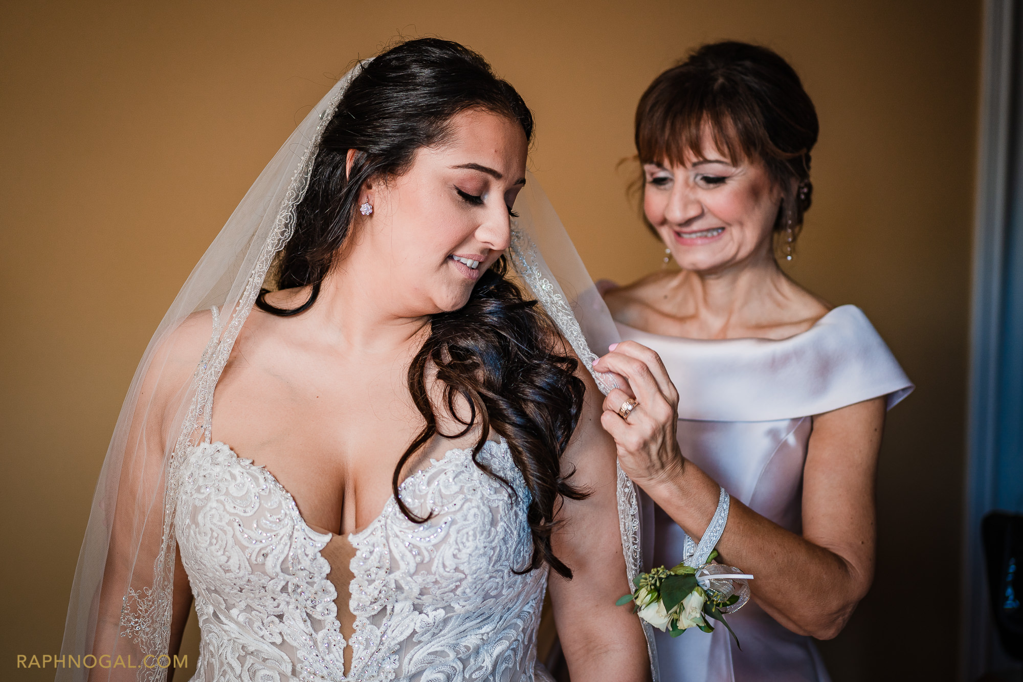 Bride's mother helping bride put on the veil